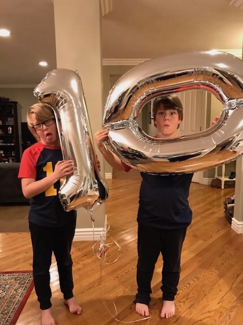 twin boys holding 10 balloons advocate