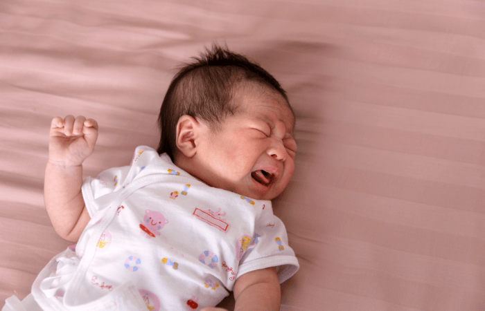 baby crying on a bed