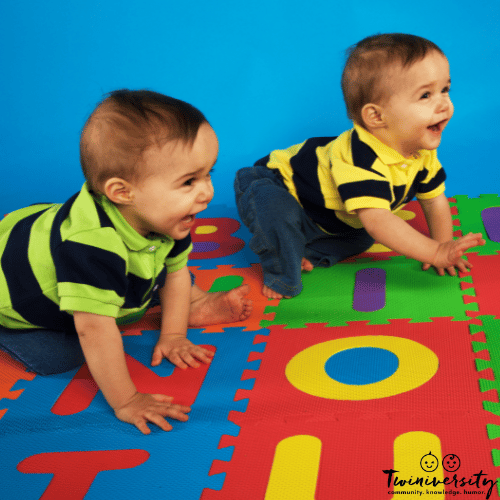 twin toddler boys crawling on a foam mat