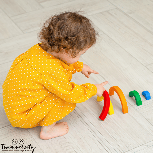 a toddler plays independently with a rainbow stacking toy