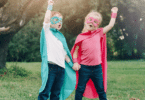 two children with superhero outfits and hands aimed at the sky
