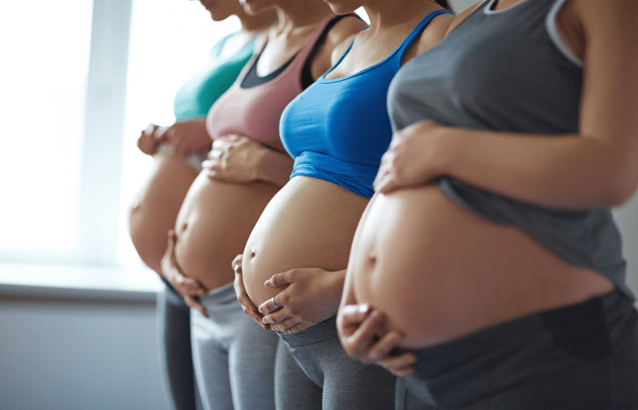 4 pregnant women holding their pregnant bellies