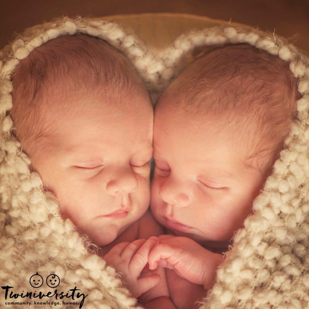 twin babies snuggled together in a blanket after a normal twin pregnancy