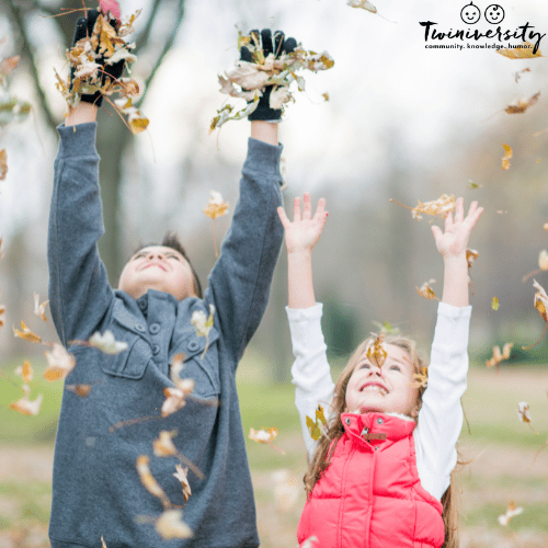 two children toss leaves into the air for fall family fun outdoors