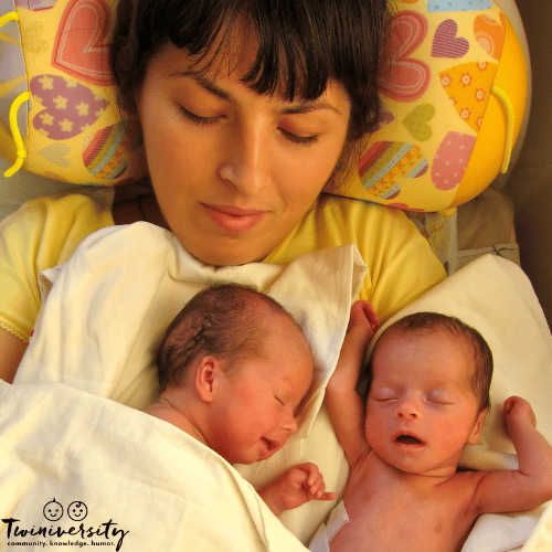 a woman holds her identical twins after birth