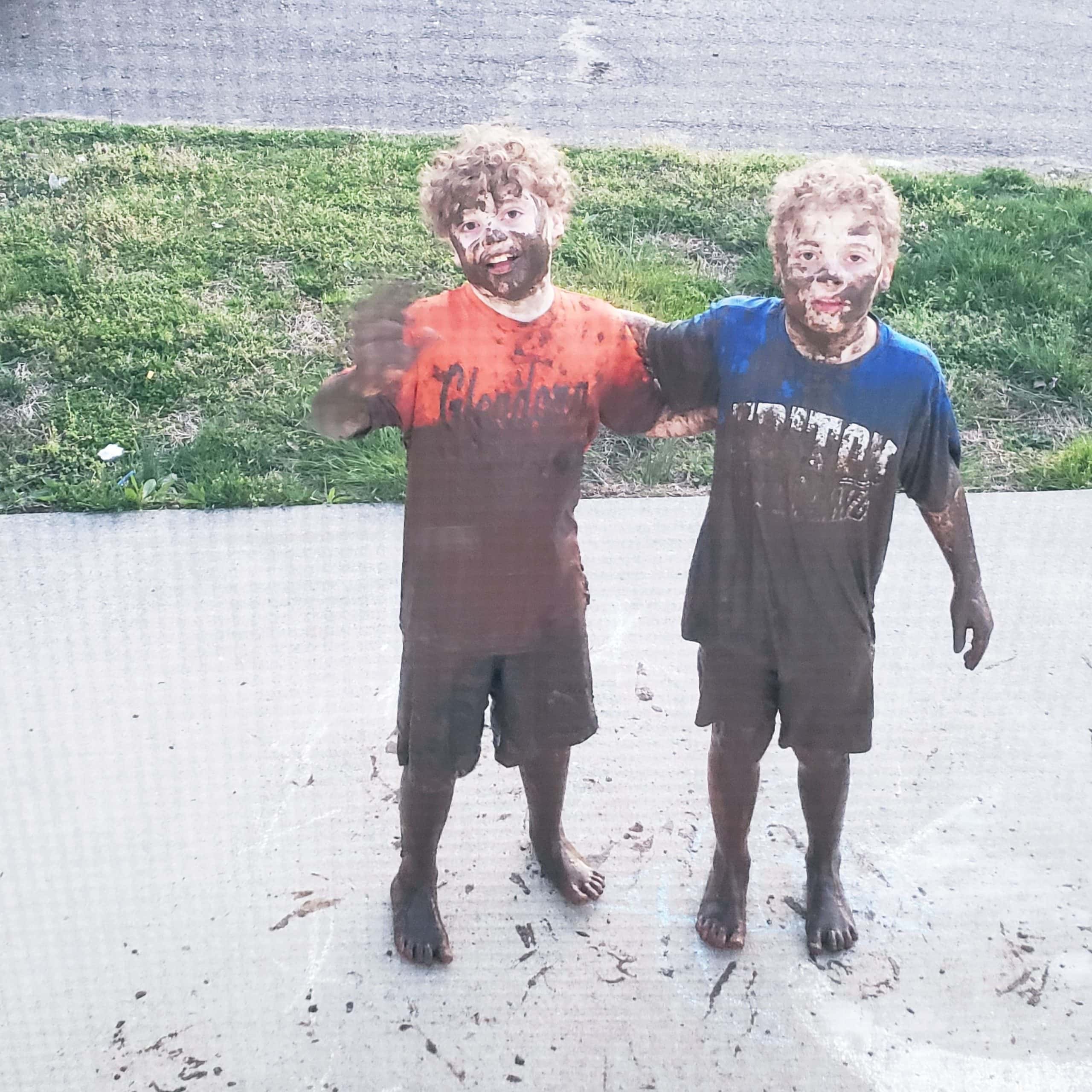 twin boys happily covered in mud.