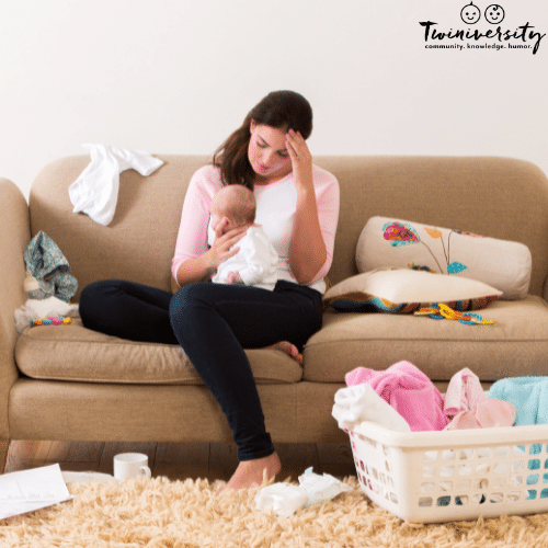 mom and baby sitting on couch with laundry and mess