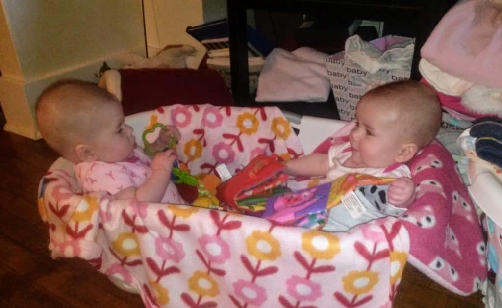 twin babies sitting in a laundry basket playing