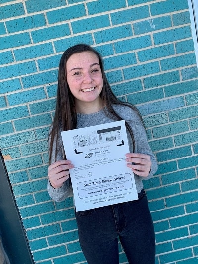 teen driver smiling while holding her new drivers license