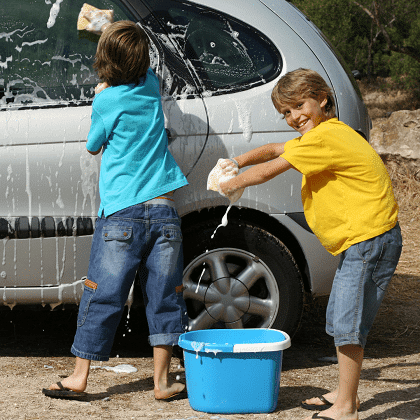 chores for 6-year-olds two boys cleaning the outside of a van with soapy water on big sponges