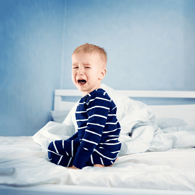 toddler bed for twins boy kneeling on bed crying