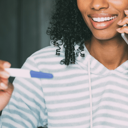 twins ultrasound woman smiling while holding a pregnancy test and talking on the phone