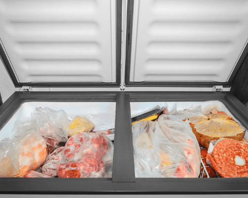 leftover Halloween candy opened chest freezer with bags of various foods inside it