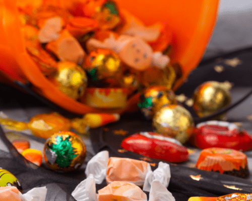 leftover Halloween candy orange candy bucket tipped over and candy spilling 