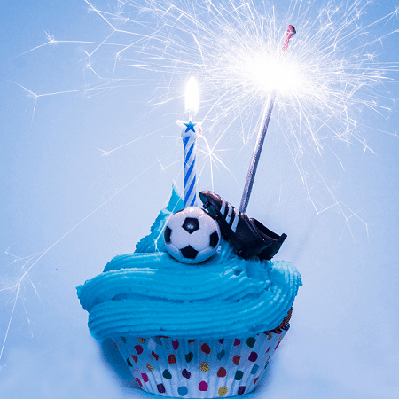 twins' birthday soccer themed cupcake with candles, soccer ball, and cleats.