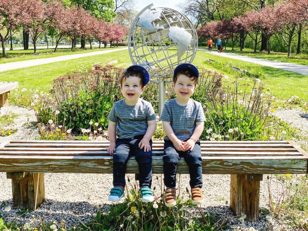 twin toddler boys sitting on a bench dressing twins alike