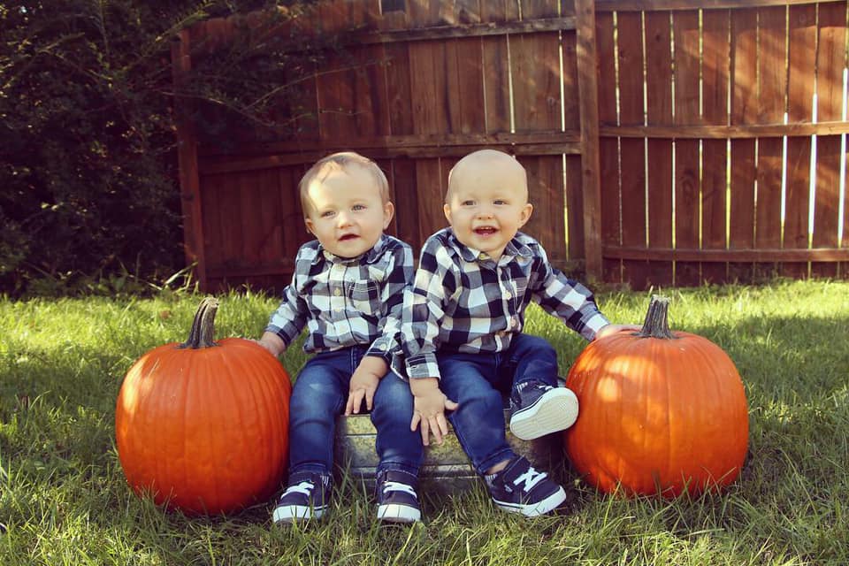 twin toddlers sitting by pumpkins dressing twins alike