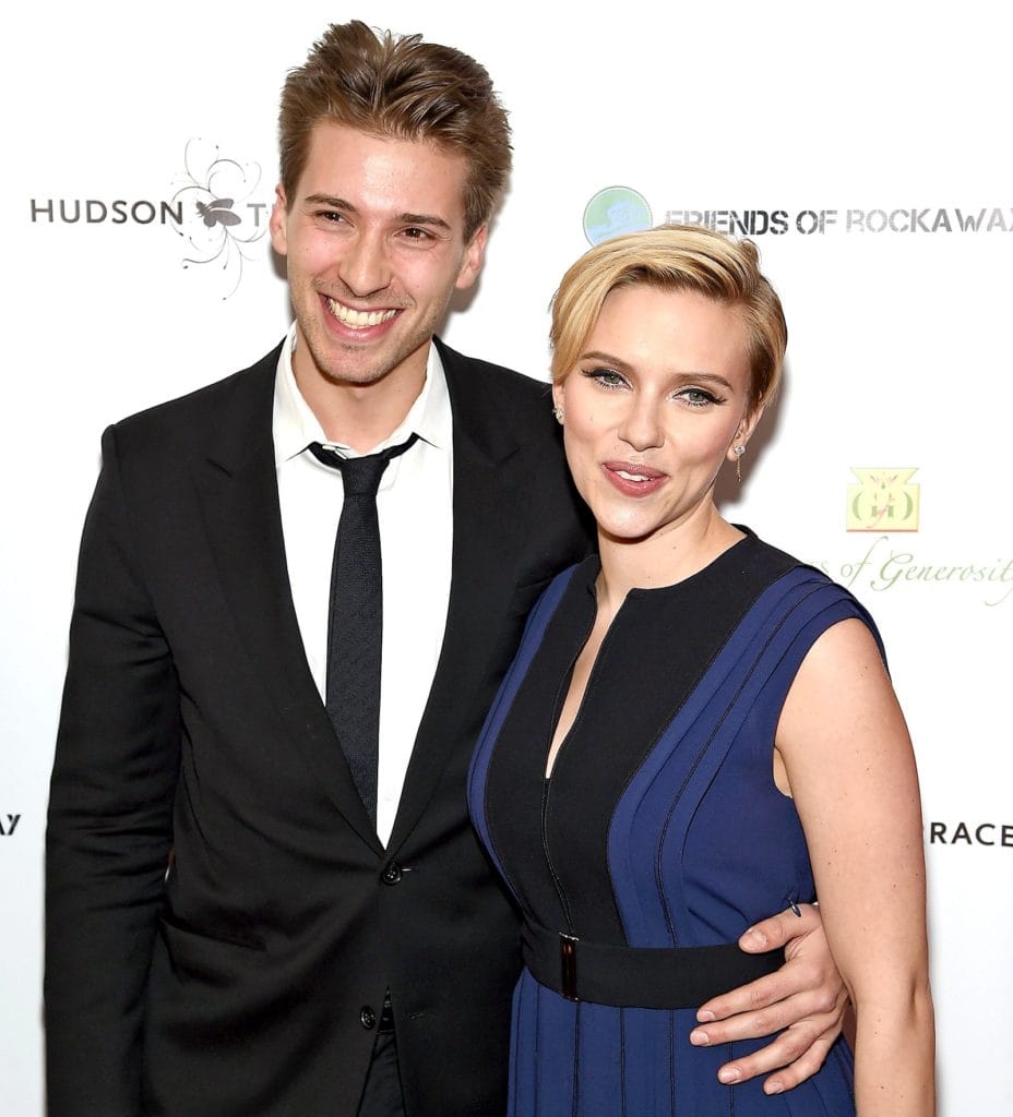 celebrity twins Scarlett Johansson and Hunter Johansson smiling arm in arm on a red carpet.