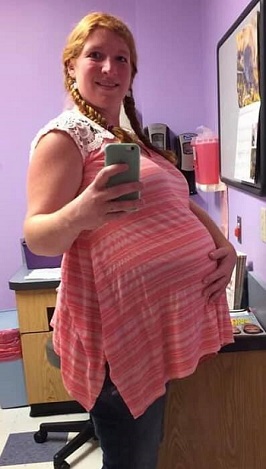 pregnant with twins belly woman holding her pregnant belly with one hand and phone with the other taking a mirror selfie