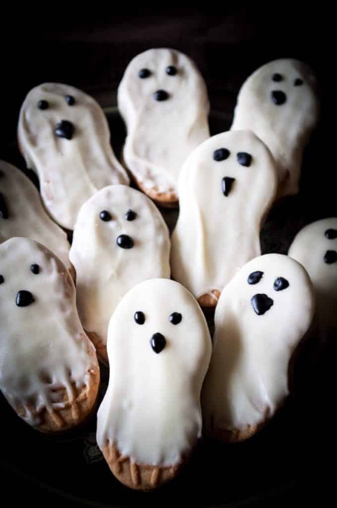 ghost cookies nutter butters dripping with white chocolate and eyes and a nose drawn on