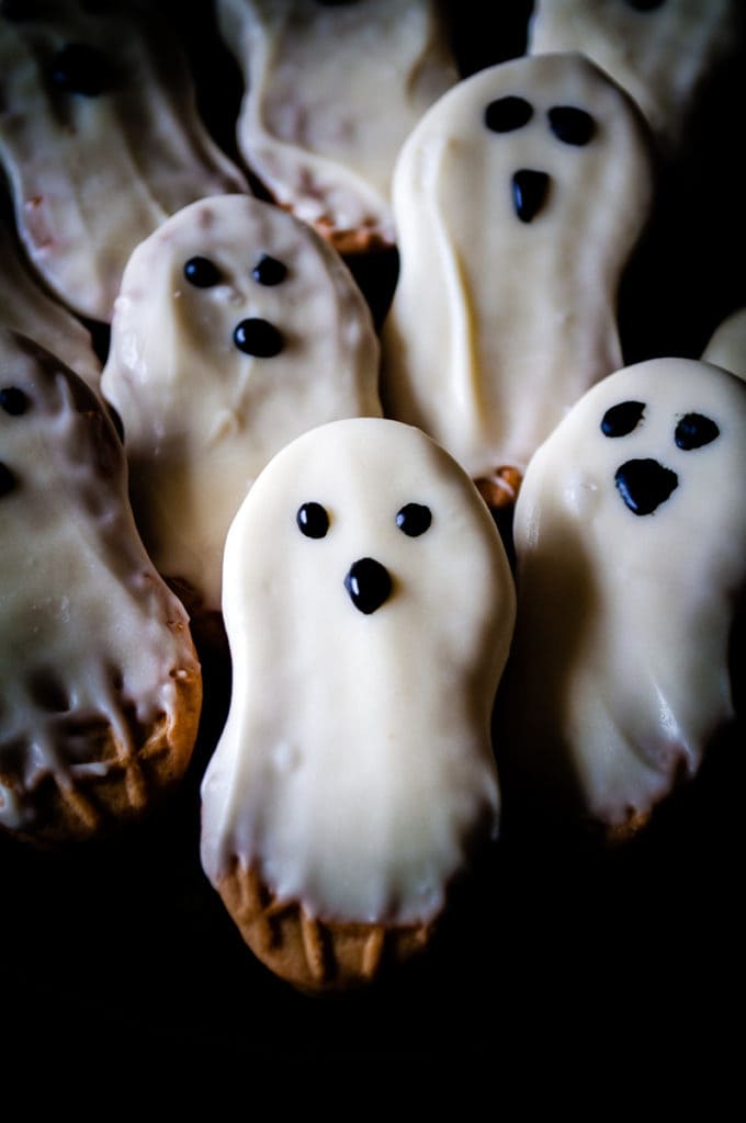 ghost cookies close up of nutter butters dripping with white chocolate and eyes and a nose drawn on