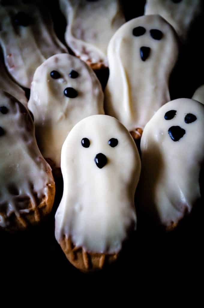 ghost cookies close up of nutter butters dripping with white chocolate and eyes and a nose drawn on