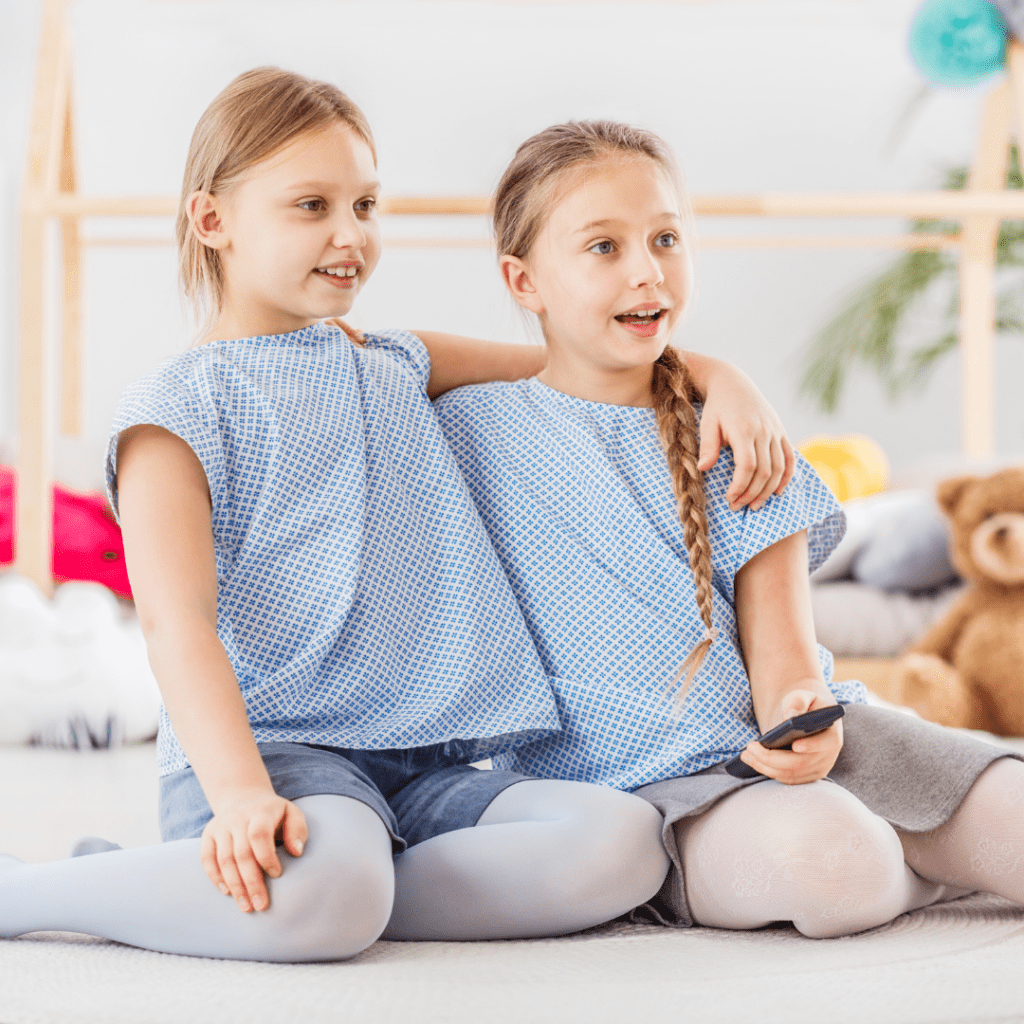 twins tv show twin girls smiling and holding tv remote