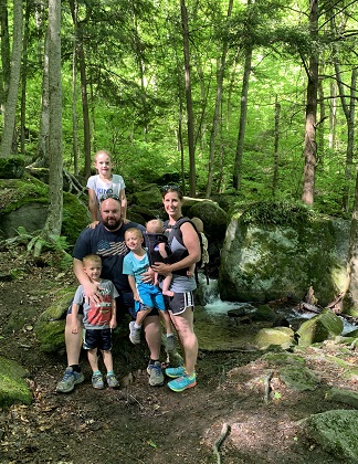 physical activities a family in the woods posing around a large rock