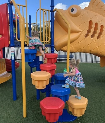 physical activities 2 girls climbing on big plastic pieces of playground equipment