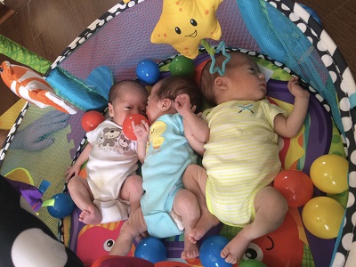 having triplets 3 infants laying next to one another in a baby lay center