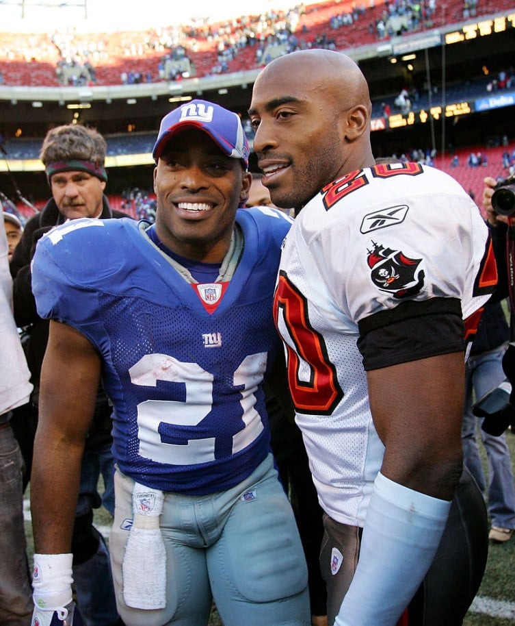 celebrity twins identical twin brother wearing opposing football uniforms in a stadium, posing for pictures