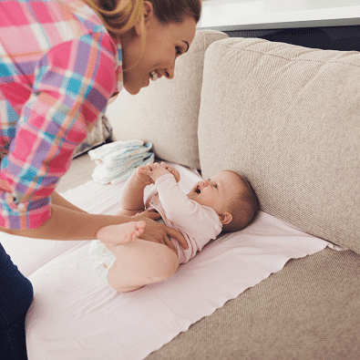 stroller blanket a woman smiling at a baby laying on her back on a receiving blanket on a couch