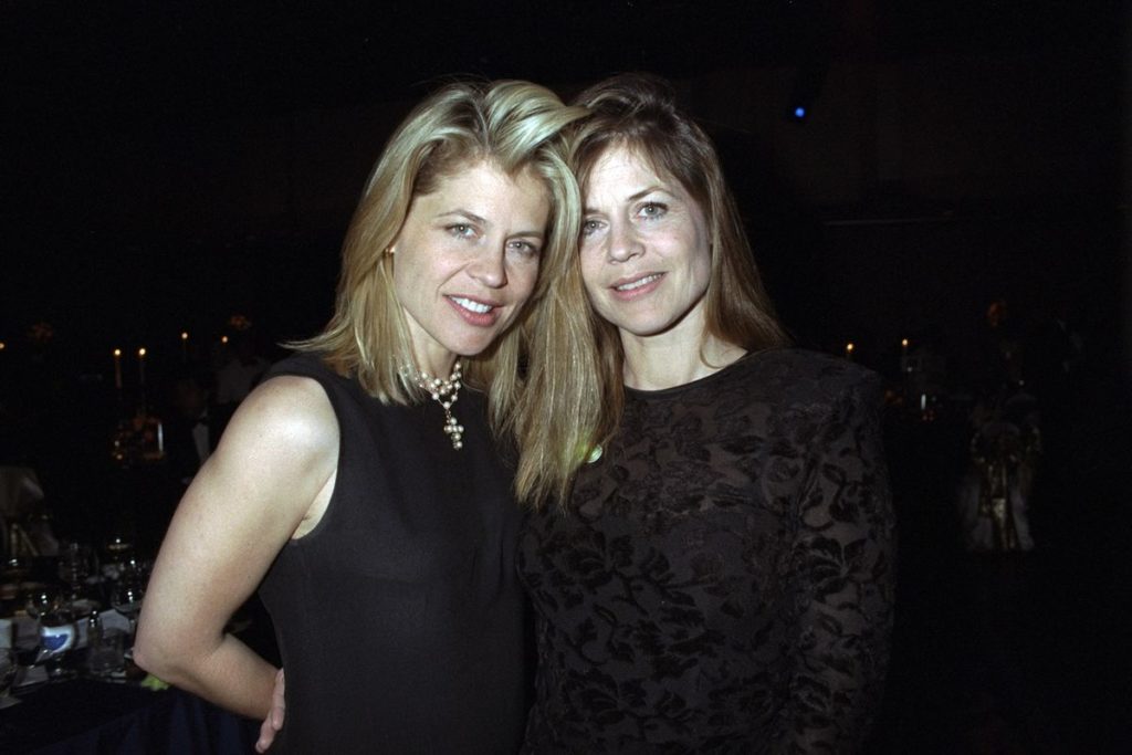 celebrity twins Linda and Leslie Hamilton standing next to one another, both dressed in black, smiling