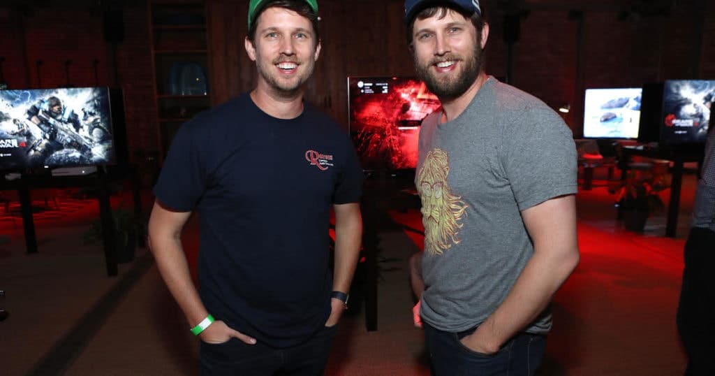 celebrity twins Jon and Dan Heder standing next to one another smiling at the camera