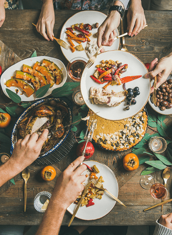 Thanksgiving dinner hands passing food around a table and serving on plates