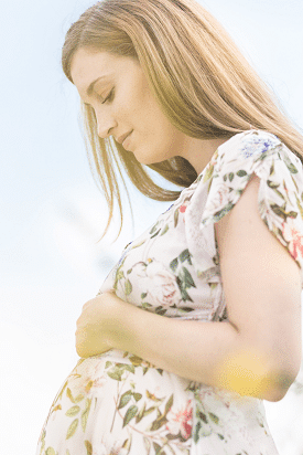 maternity baby shower dress. A woman cradling her baby bump