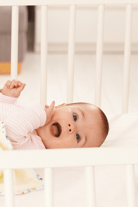 best crib sheets a baby smiling while laying in a crib