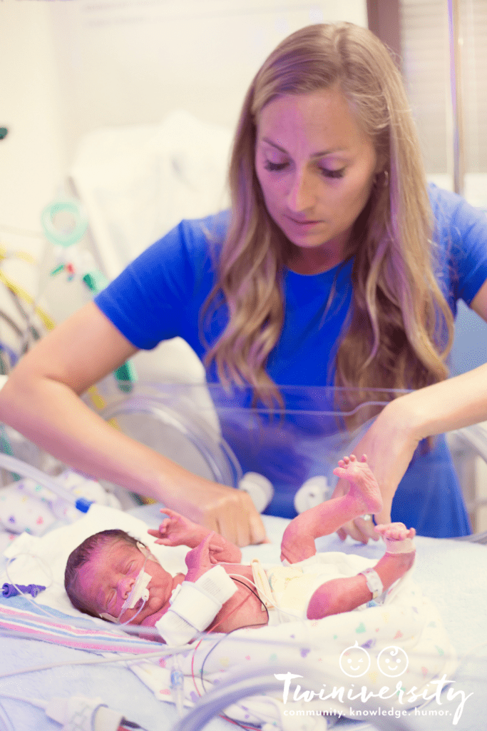 nicu nurse tending to small baby in isolette with wires