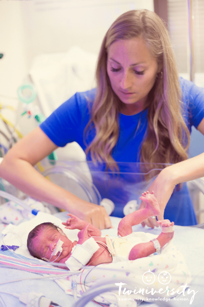 nicu nurse tending to small baby in isolette with wires 