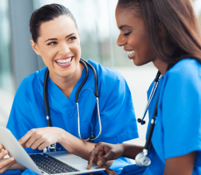 nicu nurse 2 women in scrubs talking while looking at a computer screen