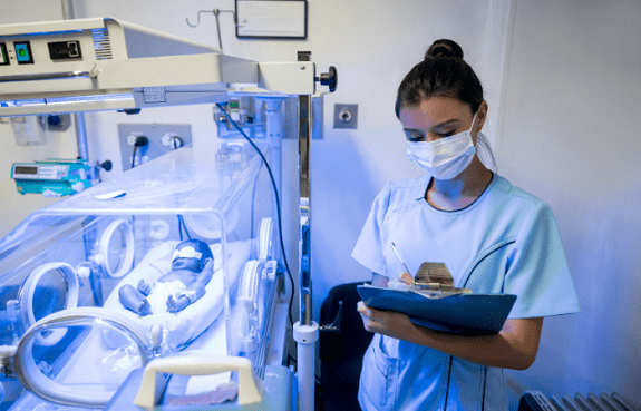 neonatologist a baby in a nicu crib and a doctor writing on a chart