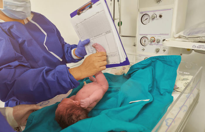 neonatologist doctor placing a newborns foot on a paper to get a record footprint