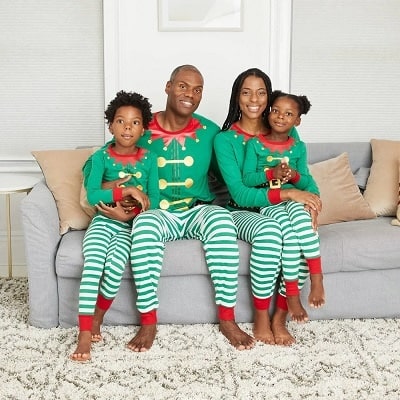 matching christmas pajamas a woman sitting with a girl in her lap and a man with his arm around a boy on a couch wearing matching pjs