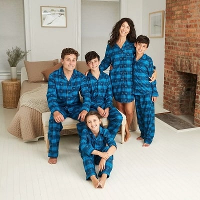 matching christmas pajamas family with matching blue fannel pajamas smiling at a camera 