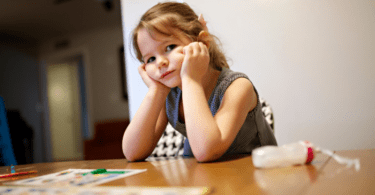 girl sitting at table looking sad stress during covid