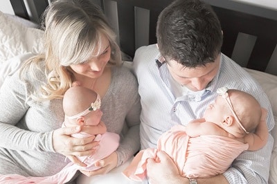 needy twins a mom and dad each holding a newborn and looking at the babies