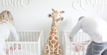 needy twins mom and dad changing diapers in cribs