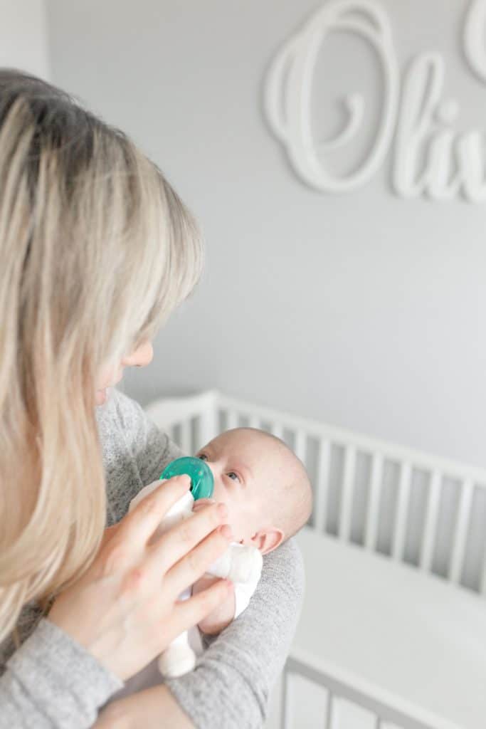 needy twins a woman holding a newborn and putting a pacifier in their mouth