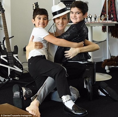 celebrities with twins celine dion with her twins boys, arms around each other and smiling back at the camera in a room with guitars on stands