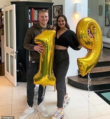 celebrities with twins fraternal twins holding a '1' and a '9' balloon for their birthday. Smiling for the camera